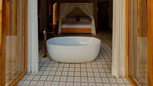 A bedroom with a large bathtub, a canopy bed, and a view through a wooden-framed window. - Hacienda La Amalia (Venecia)