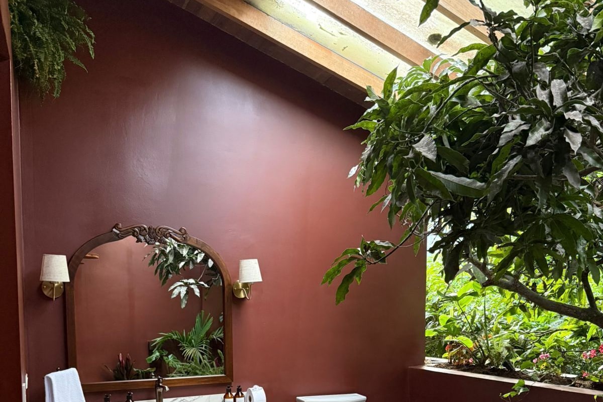 Un baño con lavamanos de mármol, inodoro, espejo y planta en maceta.