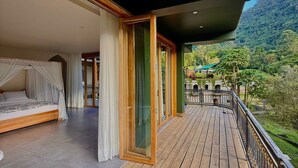 A wooden deck with a bed and curtains, a glass door, and a view of a mountainous landscape. - Hacienda La Amalia (Venecia)
