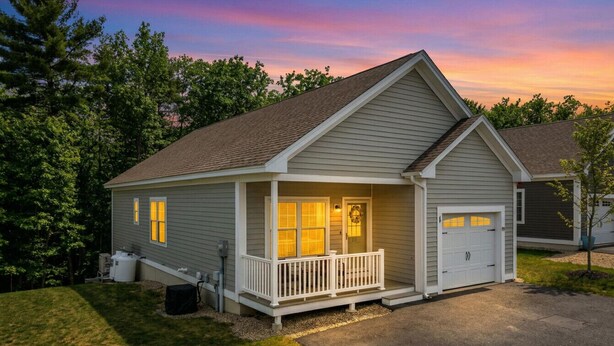 Una casa a un piano con veranda, garage e prato curato.