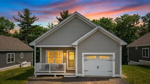 Una casa a un piano con portico anteriore, garage e vialetto.