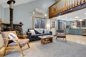 Ein gemütliches Wohnzimmer mit Kamin aus Stein, einer Couch, einem Sessel und einem Couchtisch.