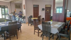 A dining area with multiple tables and chairs, a person working at a computer, and a door with a sign.