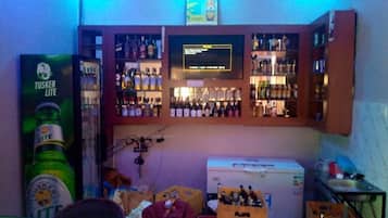 A bar area with shelves of bottles, a refrigerator, and a television screen.
