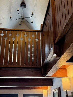 A wooden staircase with a modern light fixture above.