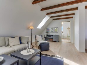 Ein modernes Wohnzimmer mit einer Couch, einem Couchtisch und einer Lampe. Eine Treppe führt zu einer oberen Ebene.