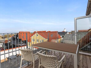 Eine Holzdar Terrasse mit Tisch und Stühlen mit Blick auf bunte Gebäude mit roten Dächern.