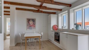 Una cocina moderna con armarios blancos, techo de madera y un amplio ventanal.