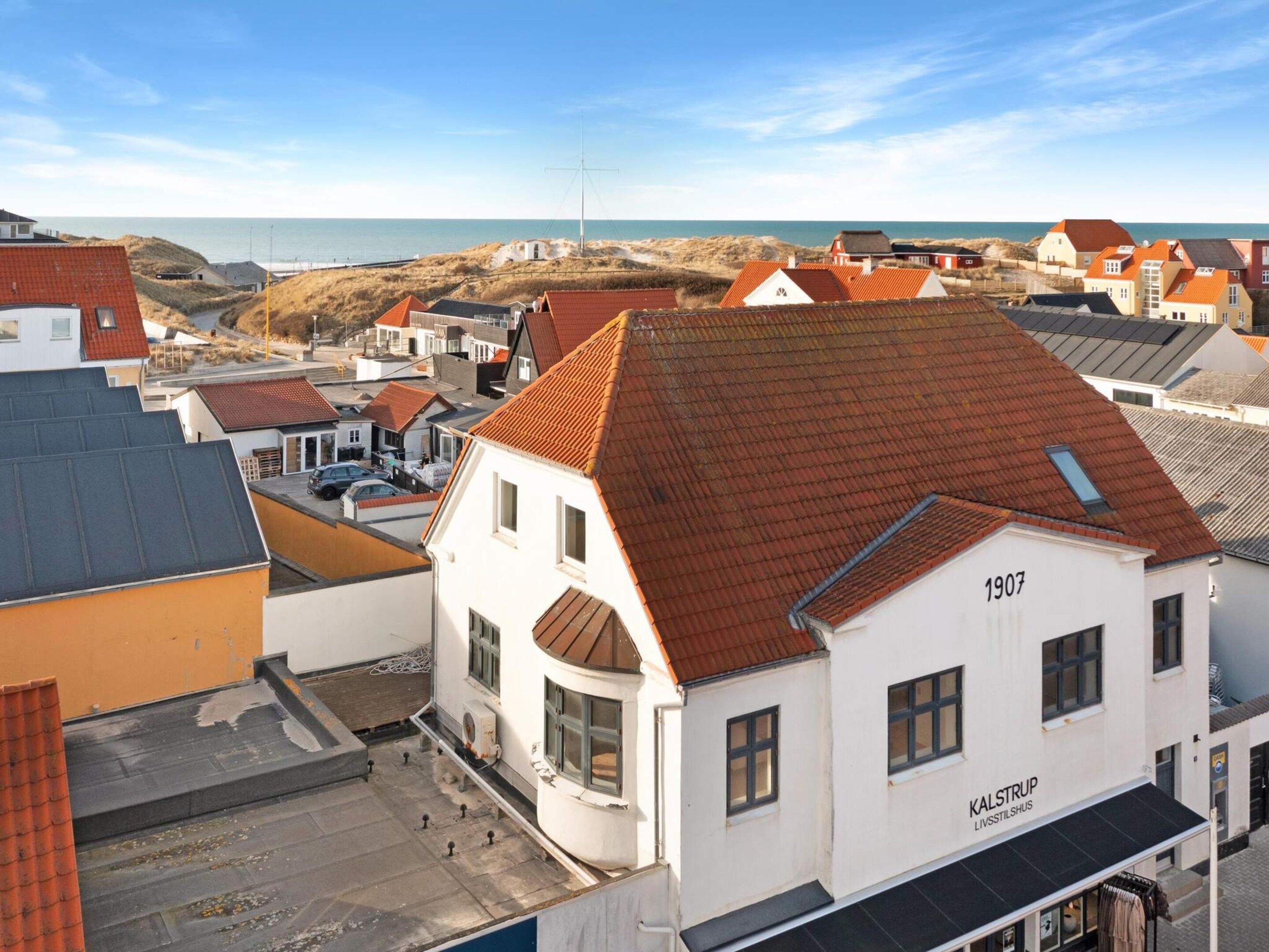 Un edificio blanco con el número 1907, techo rojo y un letrero que indica 'KALSTRUP LIVSTILHUS', posiblemente un restaurante o café.