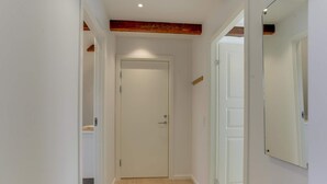 Un pasillo estrecho con suelo de madera, paredes blancas y una puerta al final.