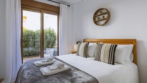 A bedroom with a bed, a view of greenery outside, and a circular wall decoration. - La Palmera (Javea / Xàbia)