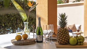 A table with a bottle of wine, glasses, fruits, and a decorative bird of paradise. - La Palmera (Javea / Xàbia)