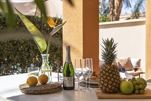 Ett bord med en vinflaska, glas, frukt och en dekorativ paradisfågel.