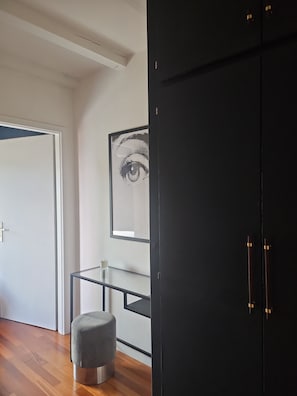 A room with a wooden floor, a grey ottoman, a glass table, a black wardrobe, and a framed artwork on the wall. - Duplex panoramic terrace with pool and sauna - Under the stars (Le Hohwald)