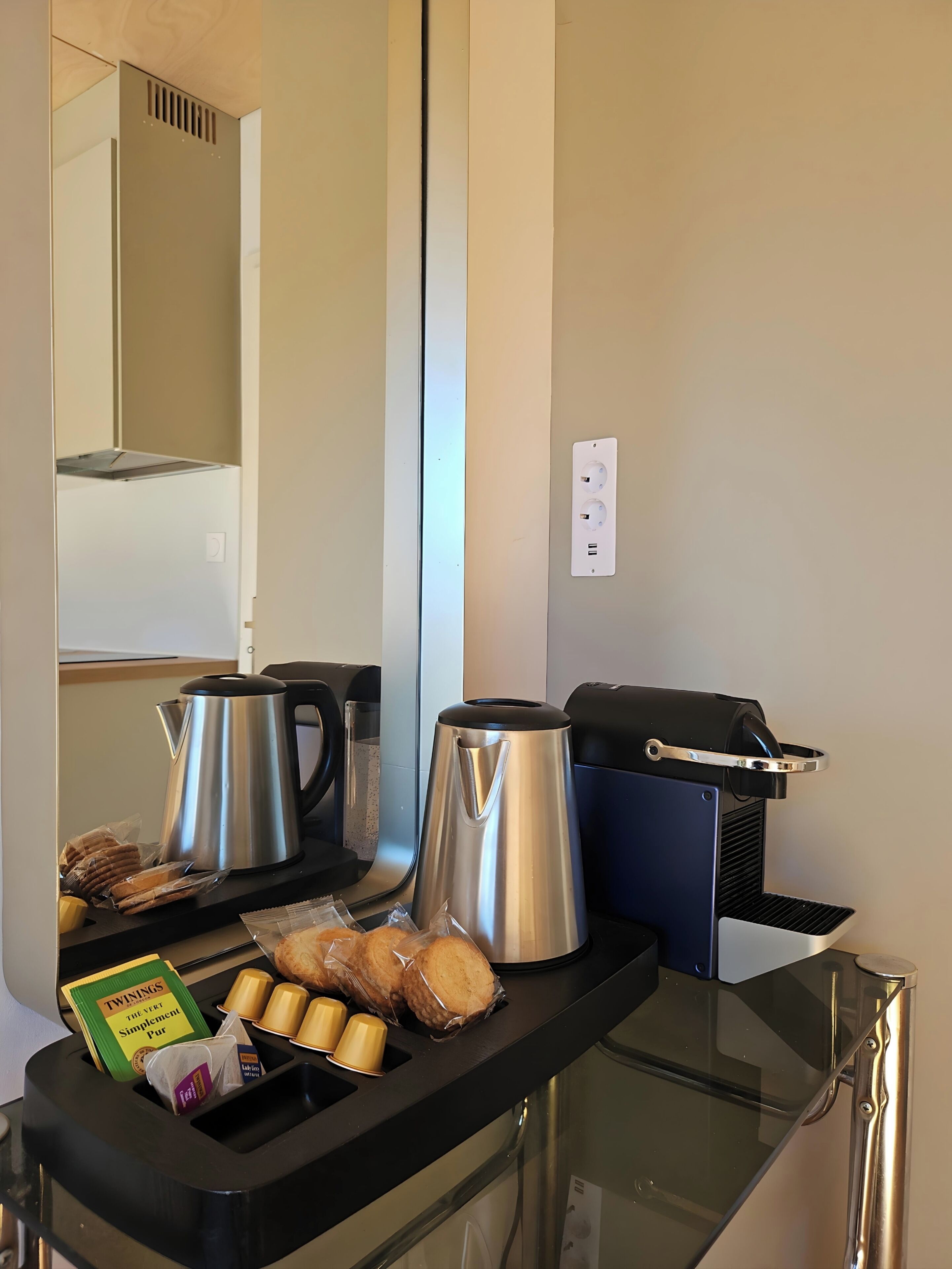 A kitchenette with a coffee maker, kettle, and packaged snacks.