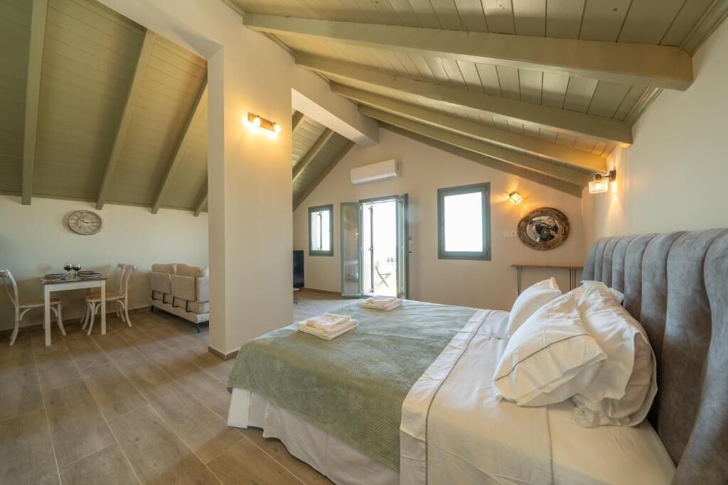 A bedroom with a bed, a desk, chairs, and a window.