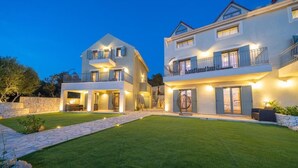 A two-story building with balconies, a stone wall, and a well-maintained lawn. - HELLOSUMMER (Kefalonia)