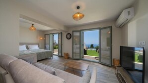 A modern bedroom with a bed, a sofa, a TV, and a balcony with a view. - HELLOSUMMER (Kefalonia)