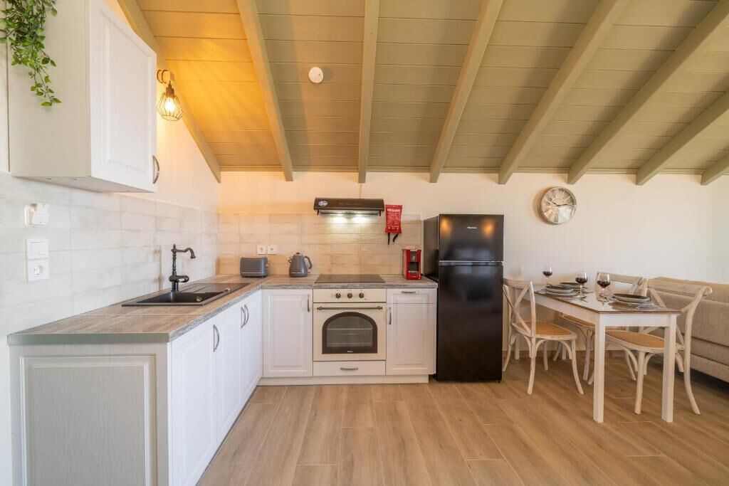 A kitchen with a stove, oven, refrigerator, and dining table with chairs.