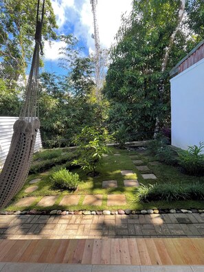 Un jardín con una hamaca, un sendero de piedra y diversas plantas.