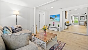 Una sala de estar moderna con un sofá, una mesa de centro y un espejo grande que refleja el ambiente.