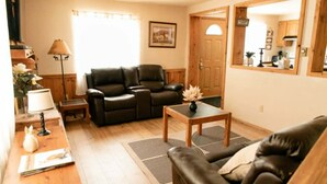 A living room with a sofa, a coffee table, a lamp, and a fireplace. - 3 bedroom Townhome in West Yellowstone, perfect for families!!! (West Yellowstone)