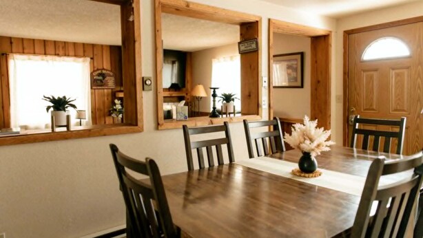 A dining room with a wooden table, six chairs, and a vase of flowers. - 3 bedroom Townhome in West Yellowstone, perfect for families!!! (West Yellowstone)