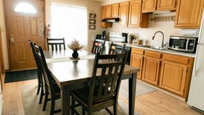 A kitchen with wooden cabinets, a dining table with chairs, a microwave, and a stove. - 3 bedroom Townhome in West Yellowstone, perfect for families!!! (West Yellowstone)