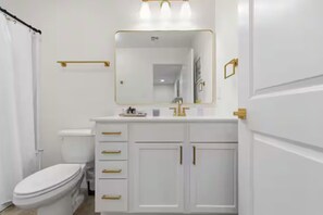A bathroom with a toilet, a sink with a mirror, and a shower curtain.