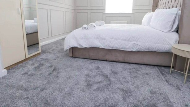 Um quarto com uma cama, mesa de cabeceira, guarda-roupa e janela.