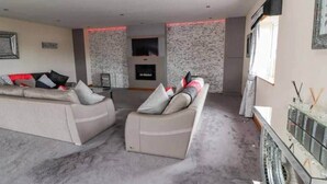 A living room with a sofa set, a flat-screen TV, and a fireplace. - Penthouse apartment in the heart of towyn (Towyn)