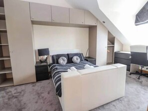 A bedroom with a bed, bedside tables, a desk, and built-in shelving.