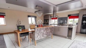 A modern kitchen with a dining area, including a bench and a table. - Penthouse apartment in the heart of towyn (Towyn)
