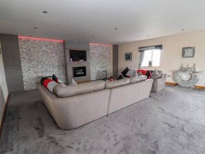 A modern living room with a large sectional sofa, a fireplace, and a decorative wall.