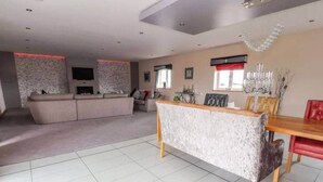 A spacious living area with a sofa set, a dining table with chairs, and a fireplace. - Penthouse apartment in the heart of towyn (Towyn)