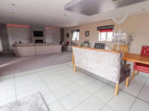 A spacious living area with a sofa set, a dining table with chairs, and a fireplace.