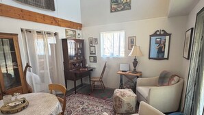 A living room with a dining table, chairs, a sofa, a patterned rug, a wooden cabinet, and a window with curtains. - Jill's place is Cozy 2 bedroom cottage on a quiet dead end road, near Cortez. (Cortez)