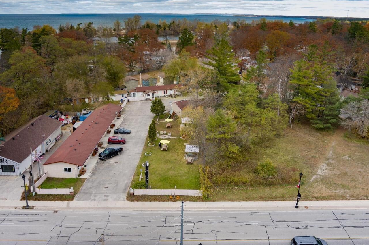 An aerial view of a residential area with houses, a parking lot, and a body of water in the background.