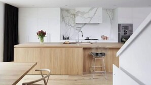 Een moderne keuken met een houten aanrecht, een marmeren achterwand en een rvs-afzuigkap.