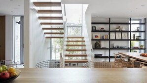 Een moderne keuken met een houten trap, een eethoek en een boekenkast.