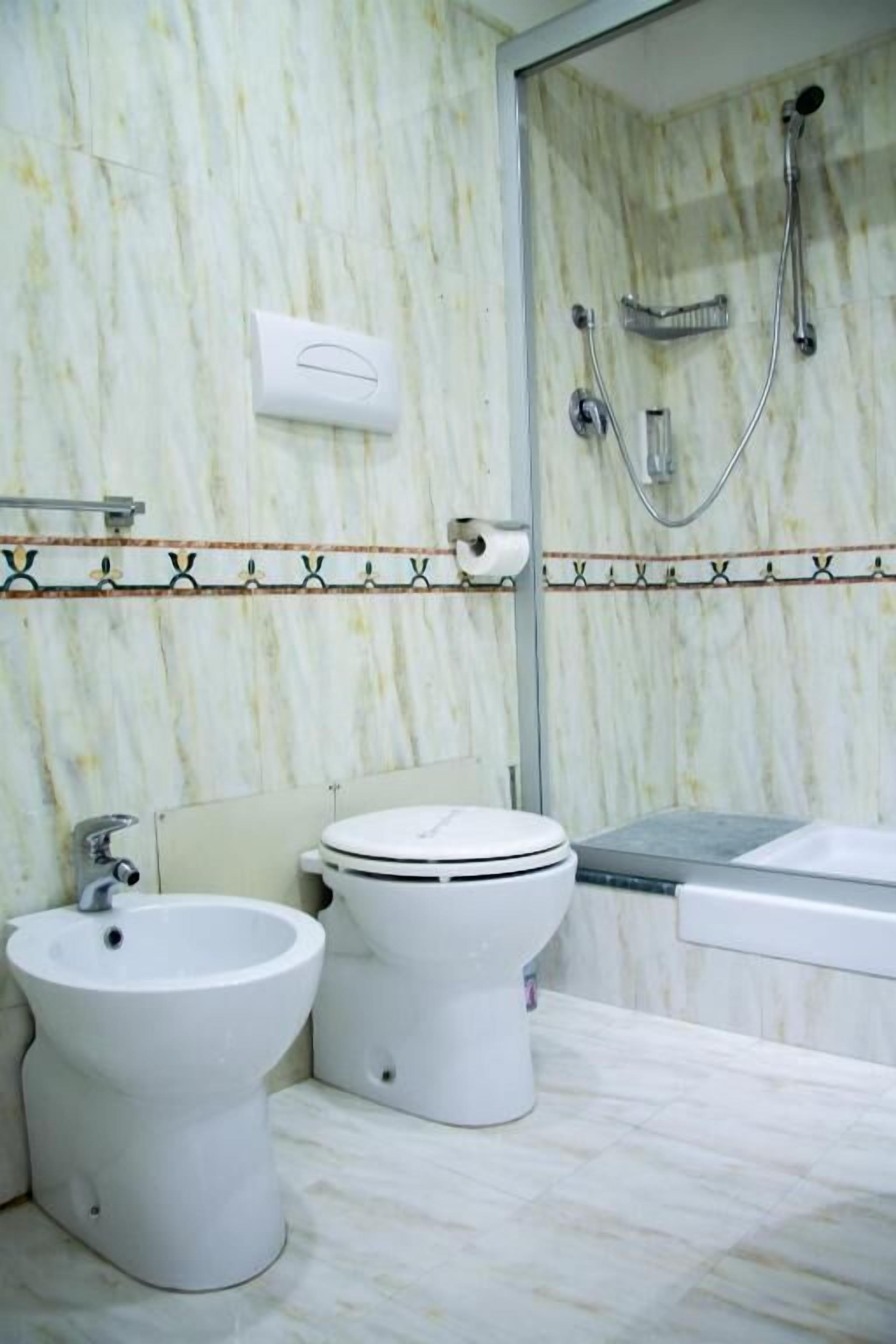 A bathroom with a bidet, toilet, and shower.