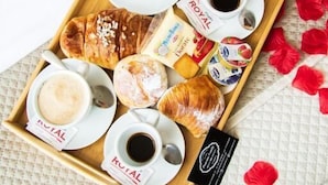 Un plateau contenant des pâtisseries, du café et une petite barre de chocolat, le tout posé sur une surface texturée.