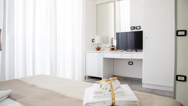 Une chambre d’hôtel comprenant un lit, un bureau avec un ordinateur, une télévision et un miroir.