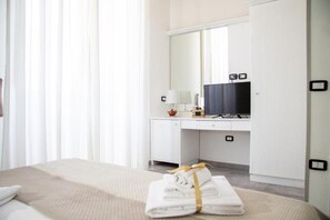 A hotel room with a bed, a desk with a computer, a television, and a mirror. - Pisacane Family (Naples)