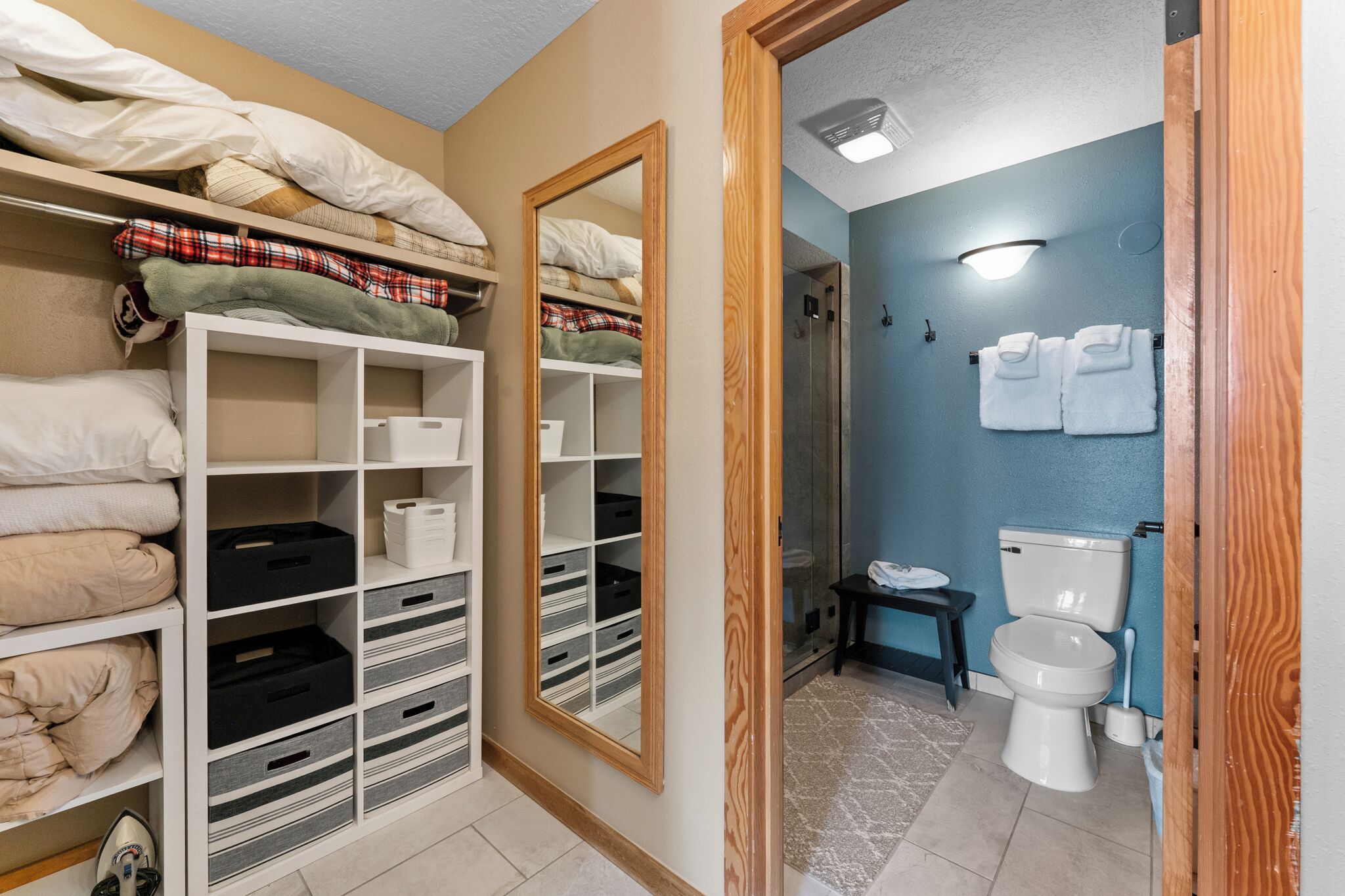 A bedroom with a wardrobe, a mirror, a bathroom with a toilet and towel rack.