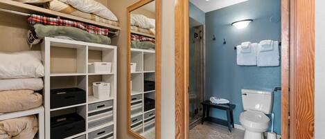 A bedroom with a wardrobe, a mirror, a bathroom with a toilet and towel rack.