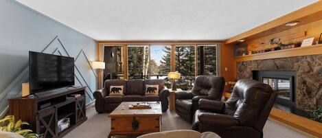 A living room with a television, leather sofas, a fireplace, and a stone wall.