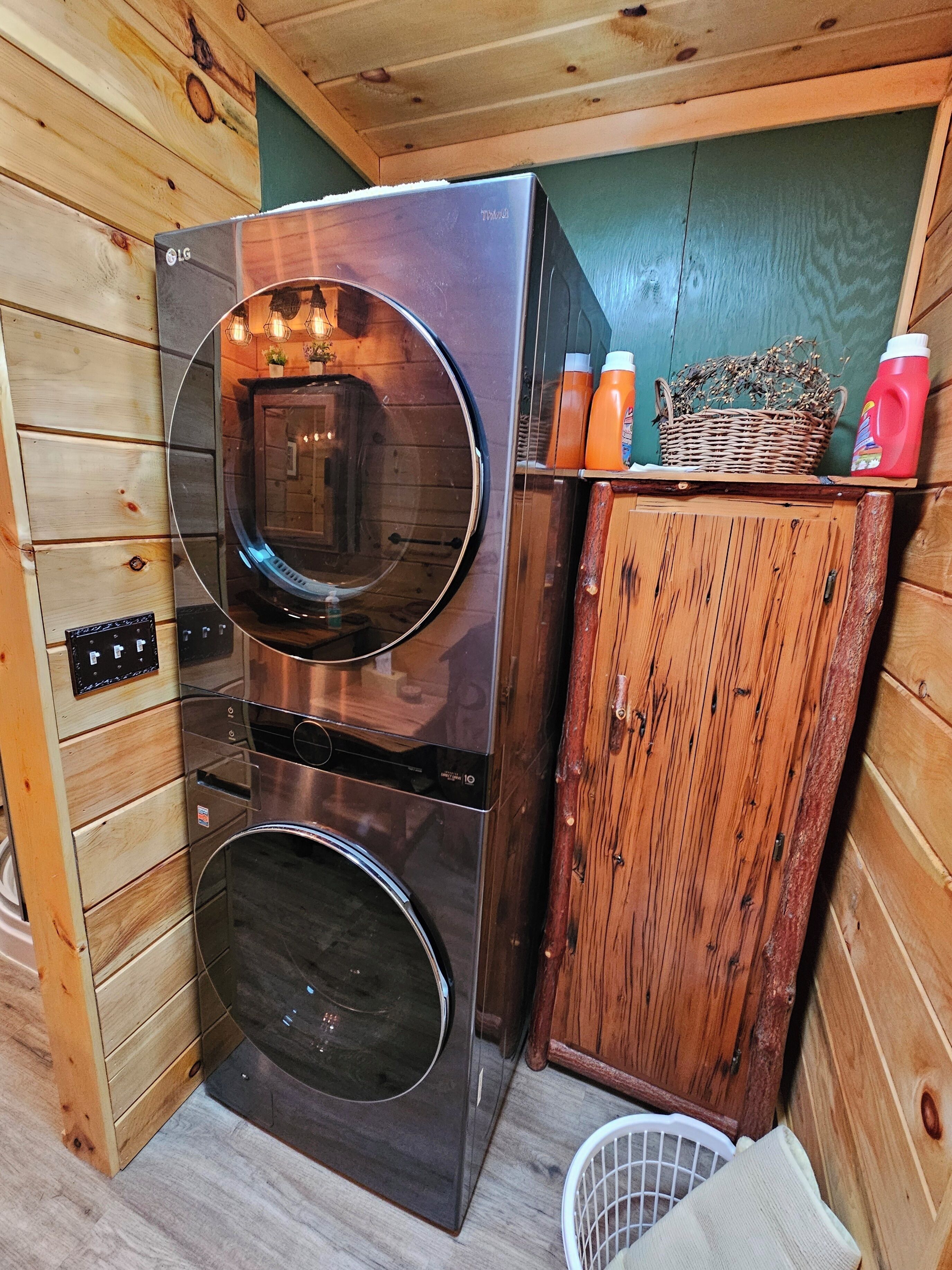Une cuisine de taille réduite, équipée d’un réfrigérateur en acier inoxydable, d’un lave-linge et d’un meuble en bois.