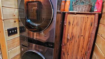 Une cuisine de taille réduite, équipée d’un réfrigérateur en acier inoxydable, d’un lave-linge et d’un meuble en bois.