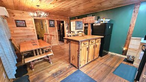 A wooden interior with a dining table, chairs, a kitchen island, and a refrigerator. - Family-Friendly Hidden Valley Cabin with Creek Views (Somerset)